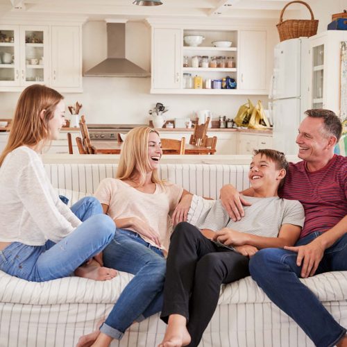 Family With Teenage Children Relaxing On Sofa Together
